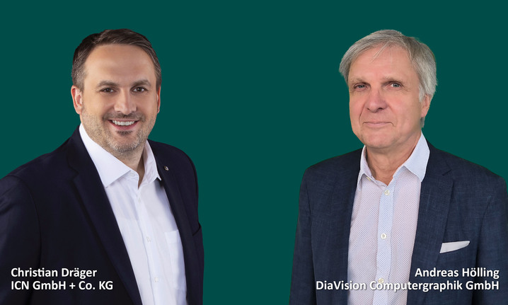 zwei Männer mittleren Alters in Business-Kleidung stehen lächelnd vor einem petrolfarbigen Hintergrund