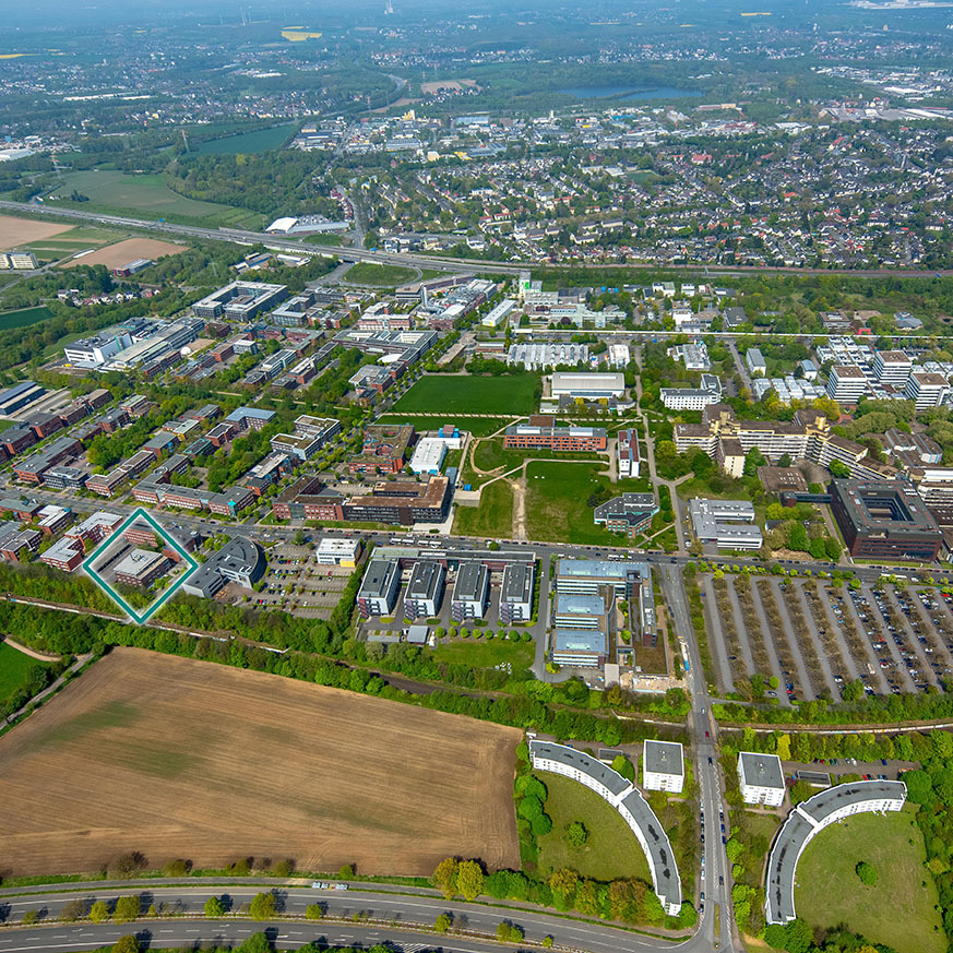 Luftaufnahme des weitläufigen Technologieparks Dortmund aus modernen Bürogebäuden, Wiesen und Parkplätzen, das ICN Gebäude ist blau umrandet